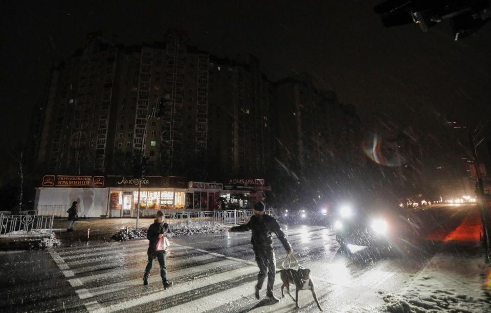 Residents cross a dark street as electricity is cut in Kyiv (EPA)