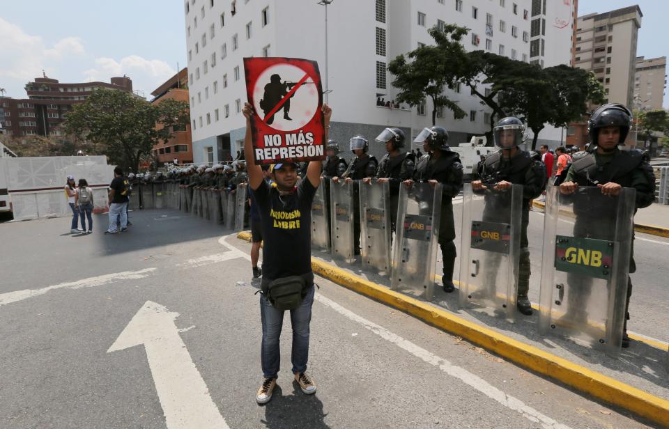 A man holds up a protest poster that reads in Spanish; "No more repression," in front of Bolivarian National Guardmen blocking a road to prevent demonstrators from arriving at the Food Ministry, in Caracas, Venezuela, Saturday, March 8, 2014. Venezuelans returned to the streets for the "empty pots march" to highlight growing frustration with shortages of some everyday items. In Caracas, the march was scheduled to end at the country's Food Ministry, but the evening before Caracas' mayor announced that he had not authorized the march. (AP Photo/Fernando Llano)