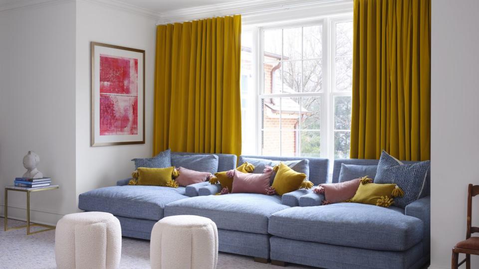 blue couch, yellow curtains, pink and yellow cushions