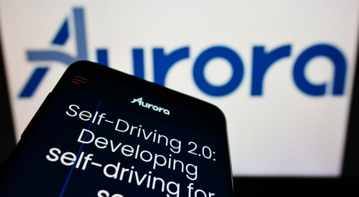 a phone displaying the Aurora website in front of a computer screen displaying the company logo