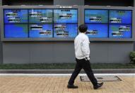 A pedestrian walks past electronic boards showing various countries' share prices outside a brokerage in Tokyo February 6, 2014. REUTERS/Toru Hanai