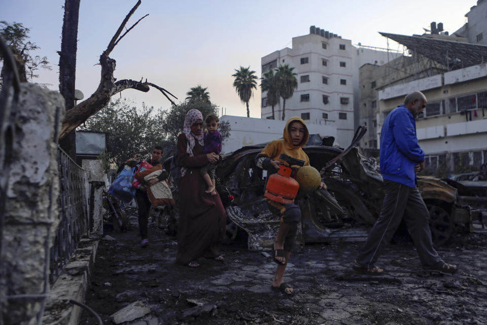 Palestinians carry belongings as they leave al-Ahli hospital, which they were using as a shelter, in Gaza City, Wednesday, Oct. 18, 2023. The Hamas-run Health Ministry says an Israeli airstrike caused the explosion that killed hundreds at al-Ahli hospital, but the Israeli military says it was a misfired Palestinian rocket. (AP Photo/Abed Khaled)