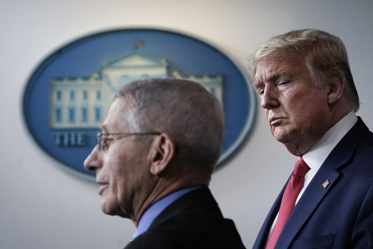President Trump frowns as Anthony Fauci speaks.