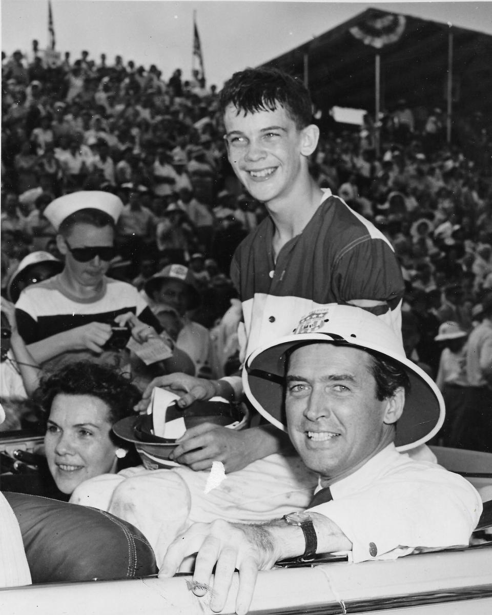 Movie star Jimmy Stewart wears a sun helmet while riding in a convertible at Derby Downs with 1947 All-American champion Kenny Holmboe, 14, of Charleston, West Virginia, and his mother, Betty Holmboe.