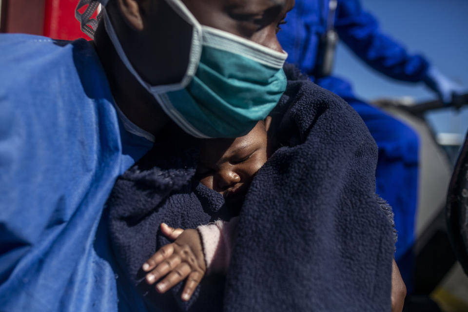 33-year old Sandrine from Cameroon holds her three months old son Moise moments before leaving the Spanish NGO Open Arms rescue vessel in the Sicilian port of Empedocle, Italy, Tuesday, Feb. 16, 2021. Various African migrants drifting in the Mediterranean Sea after fleeing Libya on unseaworthy boats have been rescued. In recent days, the Libyans had already thwarted eight rescue attempts by the Open Arms, a Spanish NGO vessel, harassing and threatening its crew in international waters. (AP Photo/Bruno Thevenin)