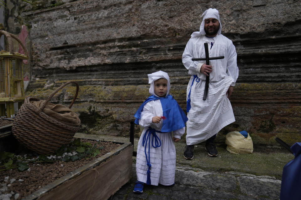 Simone, 4-year old, stands next to his father Paolo before a procession in Procida Island, Italy, Friday, March 29, 2024. Italy is known for the religious processions that take over towns big and small when Catholic feast days are celebrated throughout the year. But even in a country where public displays of popular piety are a centuries-old tradition, Procida's Holy Week commemorations stand out. (AP Photo/Alessandra Tarantino)