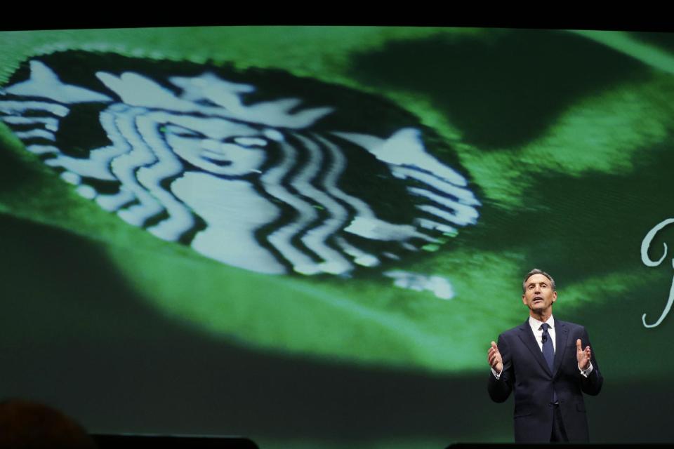 Howard Schultz, chairman and CEO of Starbucks Coffee Company, speaks in front of an image of the Starbucks logo on the green aprons worn by Starbucks workers, Wednesday, March 19, 2014, at the company's annual shareholders meeting in Seattle. (AP Photo/Ted S. Warren)