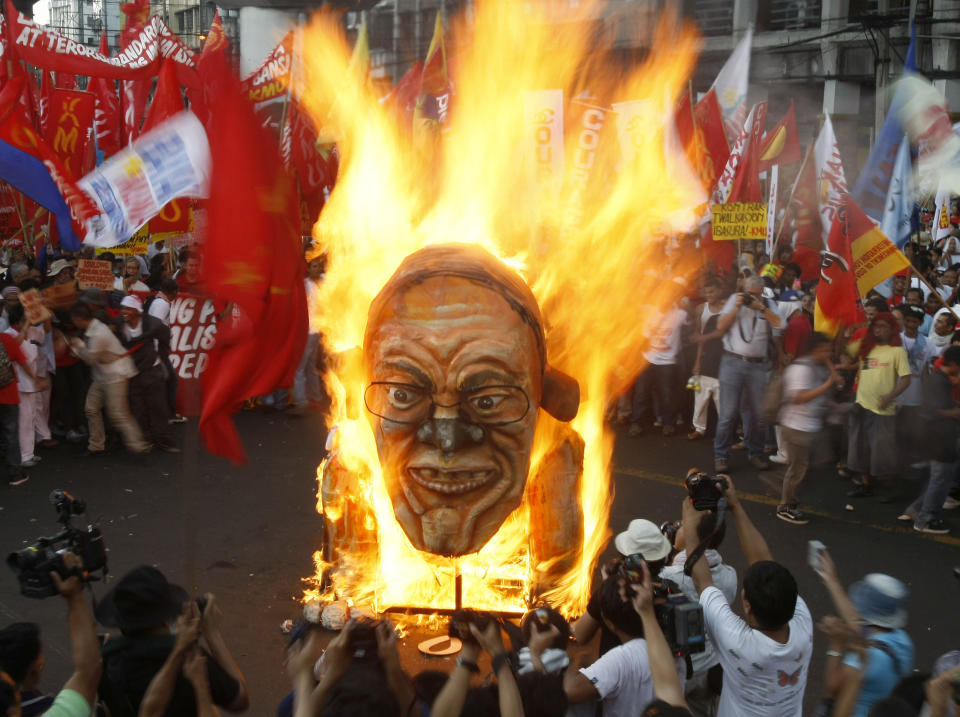 Protesters burn an effigy of Philippine President Benigno Aquino III during a rally near the Presidential Palace in Manila to celebrate international Labor Day known as May Day Tuesday May 1, 2012 in the Philippines. Thousands of workers marched under a brutal sun in Manila to demand a wage increase amid an onslaught of oil price increases, but the Philippine President rejected a $3 daily pay hike which the workers have been demanding since 1999 and warned may worsen inflation, spark layoffs and turn away foreign investors. (AP Photo/Bullit Marquez)
