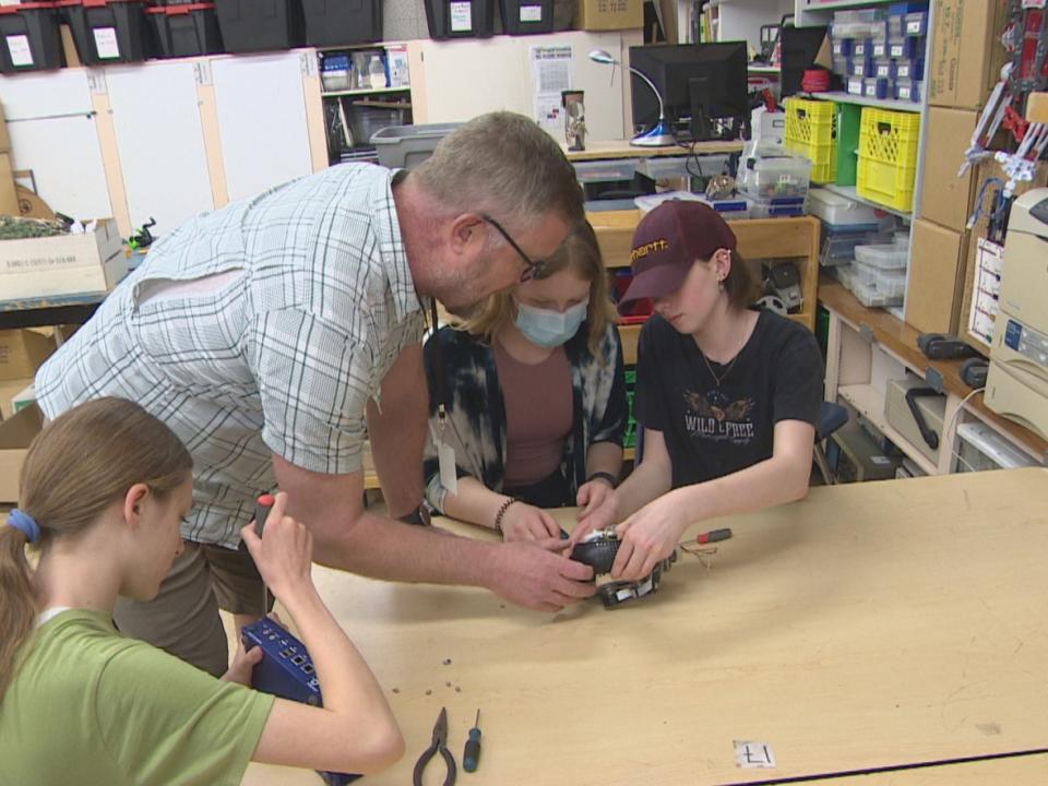 Teacher David Crowell helps students take apart an electronic during class. The project started as a school-wide initiative to find reusable items in the trash. (Trevor Bothorel/CBC - image credit)