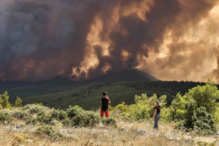 Los lugareños observan los incendios mientras se acercan al pueblo de Pournari, en el área de Magoula, a unos 25 km al suroeste de la capital griega Atenas, el 18 de julio de 2023. 