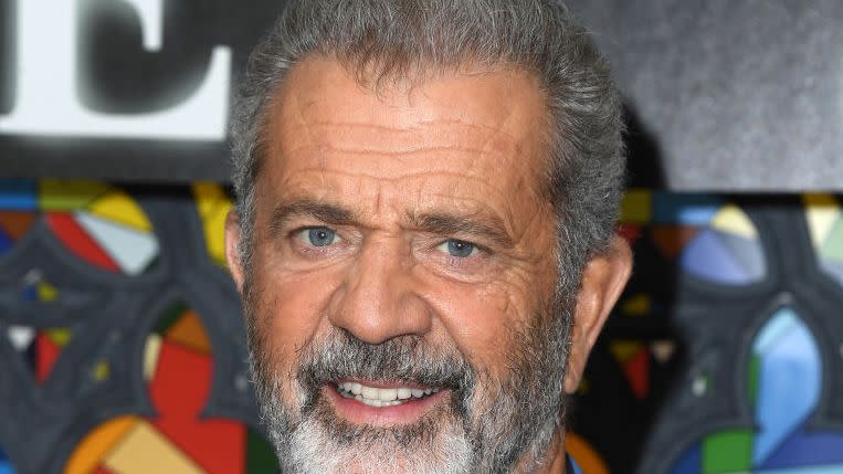 mel gibson smiling for a photograph while wearing a blue suit