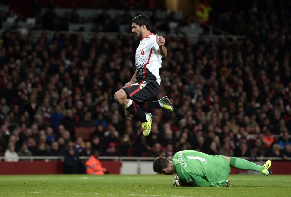 Liverpool's Suarez jumps over Arsenal's goalkeeper Szczesny during their English Premier League soccer match at the Emirates stadium in London