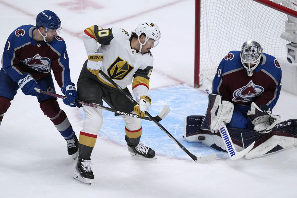 Vegas Golden Knights center Chandler Stephenson, middle, redirects the puck at Colorado Avalanche goaltender Alexandar Georgiev, right, after driving past Avalanche defenseman Devon Toews during the first period of an NHL hockey game Wednesday, Jan. 10, 2024, in Denver. (AP Photo/David Zalubowski)