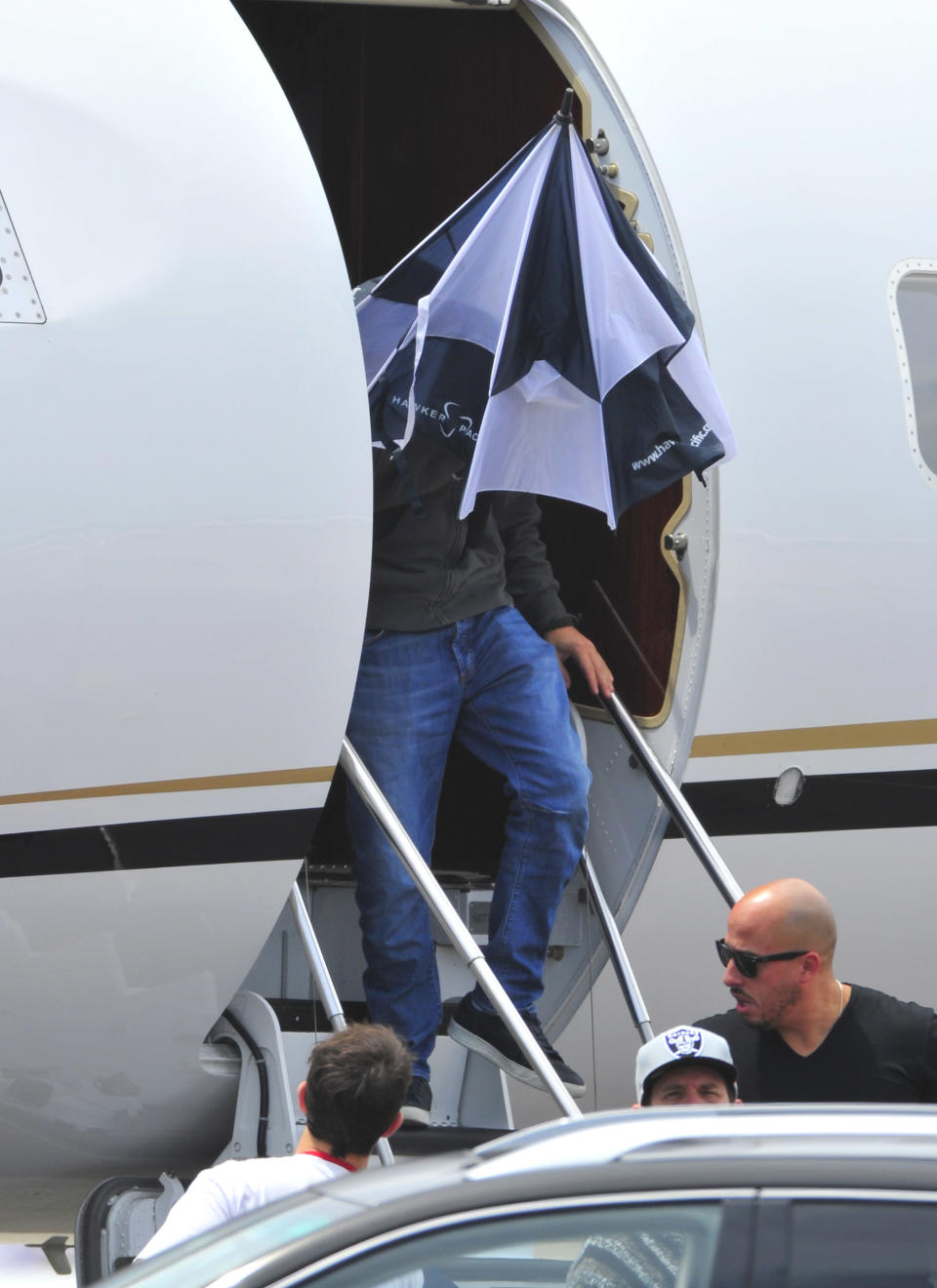 Camera-shy Leonardo DiCaprio steps off a private plane with a giant umbrella on his head. (Photo: Hot Shots Worldwide/Splash)