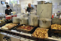 Catering manager Matthew Wright, center, prepares meals at Hillstone Primary School, in Birmingham, England, Wednesday, Nov. 30, 2022. For some children in low-income areas in England, a school lunch may be the only nutritious hot meal they get in a day. School lunches are given for free to all younger children in England and to some of the poorest families. But the Food Foundation charity estimates that there are 800,000 children in England living in poverty who are not eligible for the free meals. (AP Photo/Rui Vieira)