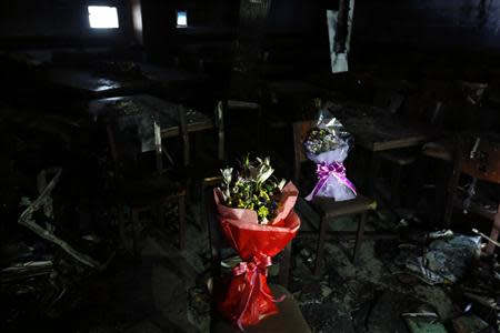 Bouquets are placed on burnt chair at a dining room of a migrant shelter destroyed by an arson attack in Seoul October 14, 2013. REUTERS/Kim Hong-Ji