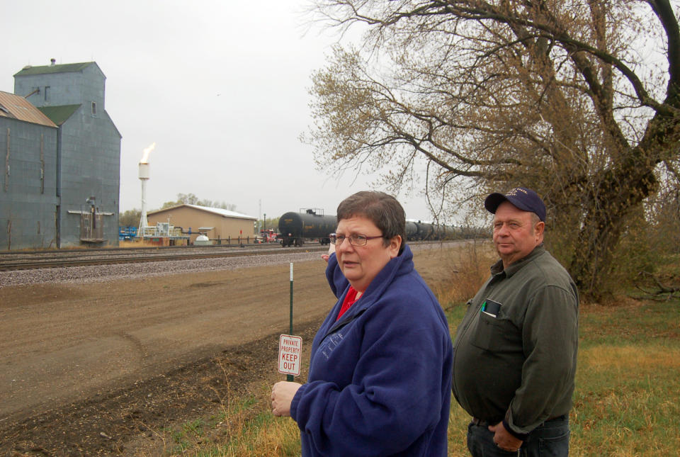 In this April 19, 2012, photo Kerry and Darrell Finsaas survey a new crude-to-rail shipping facility adjacent to their home in Dore, N.D. For more than three decades, the couple were all that kept this blink-and-you-miss-it western North Dakota city from being a ghost town. Now the region has been reborn with increased oil activity and the couple intends to move. (AP Photo/ James MacPherson)