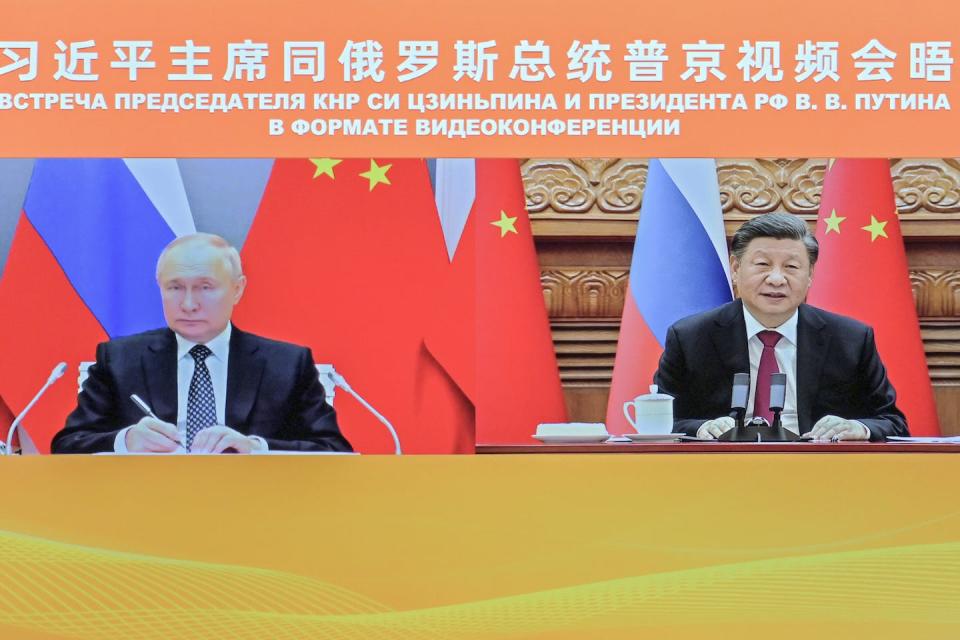 In this photo released by Xinhua News Agency, Chinese President Xi Jinping (right) and Russian President Vladimir Putin appear on screen during a meeting via video link in Beijing in December 2022. (Yue Yuewei/Xinhua via AP)