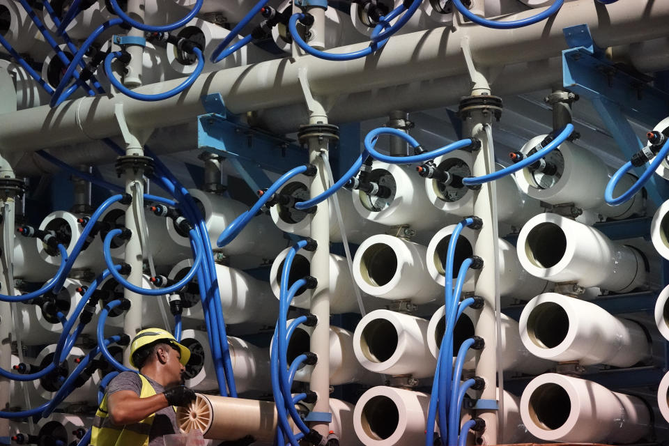 A man performs maintenance work in the reverse osmosis building at the Carlsbad Desalination plant Thursday, May 26, 2022, in Carlsbad, Calif.The facility is the Western hemisphere's largest desalination plant, which removes salt and impurities from ocean water. (AP Photo/Gregory Bull)