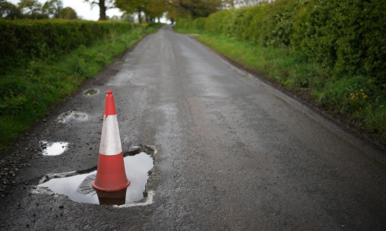 <span>A traffic cone warns drivers of a pothole on a road near Northwich.</span><span>Photograph: Christopher Furlong/Getty Images</span>