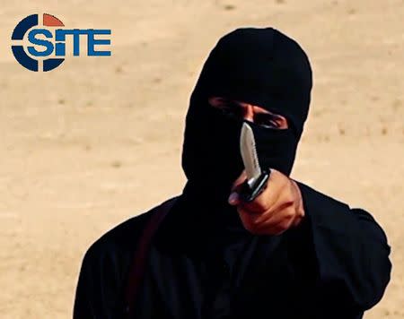 A masked, black-clad militant, who has been identified by the Washington Post newspaper as a Briton named Mohammed Emwazi, brandishes a knife in this still image from a 2014 video obtained from SITE Intel Group February 26, 2015. REUTERS/SITE Intel Group/Handout via Reuters