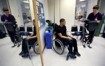 22-year-old Errol Samuels from Queens, New York, who lost the use of his legs in 2012 after a roof collapsed onto him at an off-campus house party near where he was attending college in upstate New York, sits in his wheelchair as therapist Alexandra Voigt (R) prepares a ReWalk electric powered exoskeletal suit for a therapy session with Samuels at the Mount Sinai Medical Center in New York City March 26, 2014. Made by the Israeli company Argo Medical Technologies, ReWalk is a computer controlled device that powers the hips and knees to help those with lower limb disabilities and paralysis to walk upright using crutches. Allan Kozlowski, assistant professor of Rehabilitation Medicine at Icahn School of Medicine at Mount Sinai hospital, where patients like Samuels are enrolled in his clinical trials of the ReWalk and another exoskeleton, the Ekso (Ekso Bionics) hopes machines like these will soon offer victims of paralysis new hope for a dramatically improved quality of life and mobility. The ReWalk is currently only approved by the U.S. Food and Drug Administration (FDA) for use in rehabilitation facilities like at Mount Sinai, as they weigh whether to approve the device for home use as it already is in Europe. Picture taken March 26, 2014. REUTERS/Mike Segar