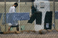 GUANTANAMO BAY, CUBA - MARCH 29: (EDITORS NOTE: Image has been reviewed by the U.S. Military prior to transmission.) A detainee walks past a row of drying laundry at Camp Delta in the Guantanamo Bay detention center on March 29, 2010 in Guantanamo Bay, Cuba. U.S. President Barack Obama pledged to close the prison by early 2010, but the administration has struggled to transfer, try or release the remaining detainees from the facility, located on the U.S. Naval base on the Caribbean island. (Photo by John Moore/Getty Images)