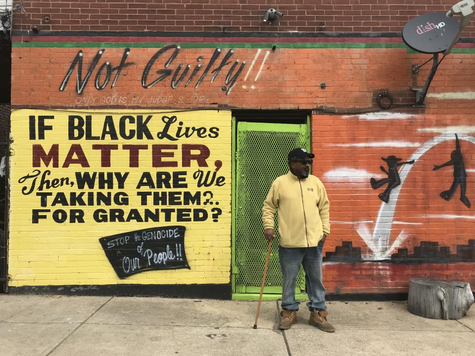 Byron Mischeaux stands in front of his barbecue restaurant in St. Louis. He says he painted these murals after he survived being shot in the head three times. (Photo: Michael Caravella and Shirley Chan/HuffPost)