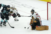 Chicago Blackhawks goaltender Marc-Andre Fleury, right, makes a stop as Seattle Kraken center Yanni Gourde (37) and Blackhawks defenseman Jake McCabe, second from left, watch the puck during the first period of an NHL hockey game, Monday, Jan. 17, 2022, in Seattle. (AP Photo/Ted S. Warren)