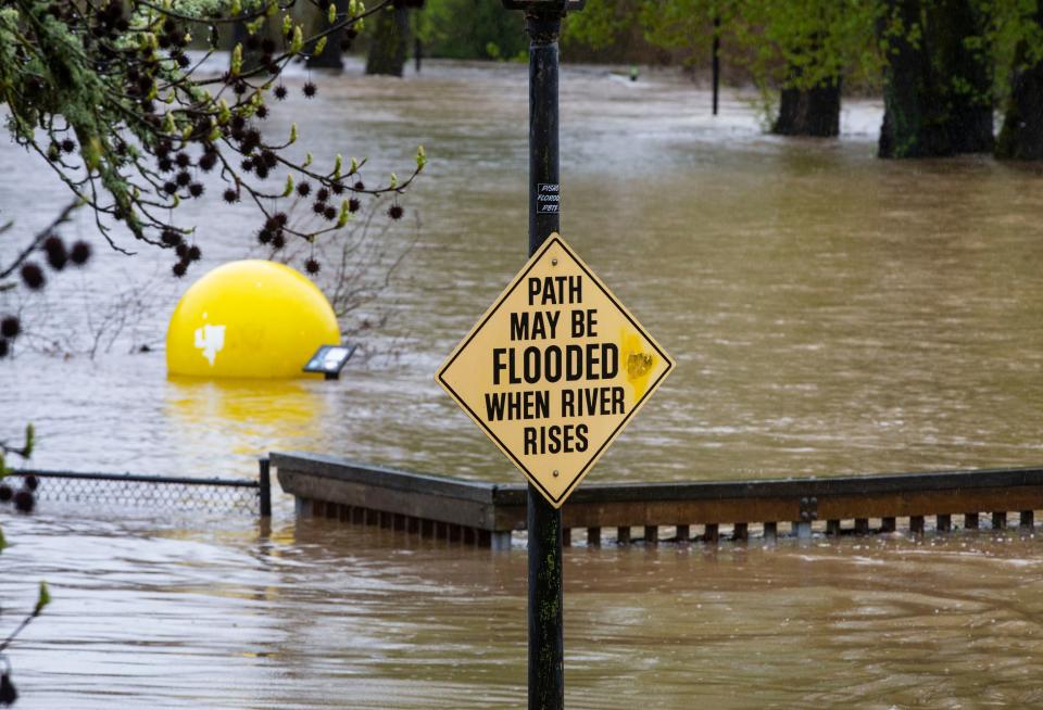 A sign warning of possible floodwaters at the entrance to Alton Baker Park in Eugene, Ore., proves to be an understatement, Monday, April 8, 2019, as water from the nearby Willamette River spills out into the park.