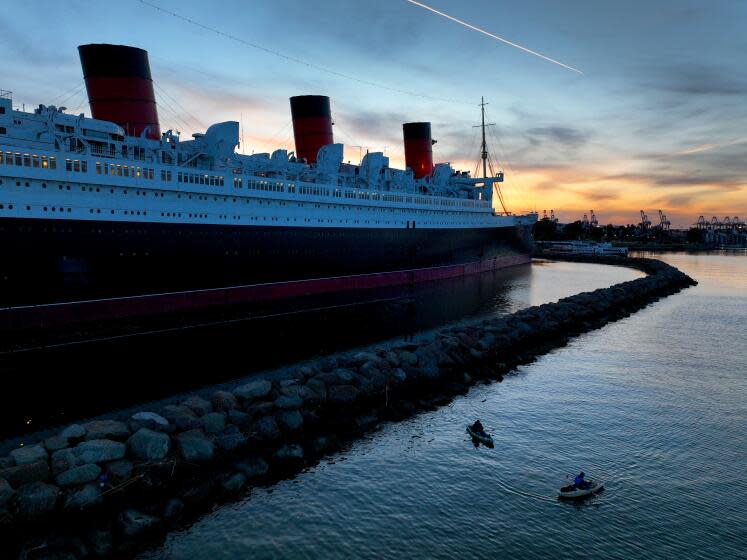 Long Beach, CA - February 17: Amid cool weather, people fish from a kayaks with a view of the historic RMS Queen Mary ocean liner, that is 1,019.4 feet long and 181 feet high at dusk Friday, Feb. 17, 2023 in Long Beach. The RMS Queen Mary was first put in service from 1936 and retired in 1967 as a ship museum and hotel, and is currently being refurbished. (Allen J. Schaben / Los Angeles Times)