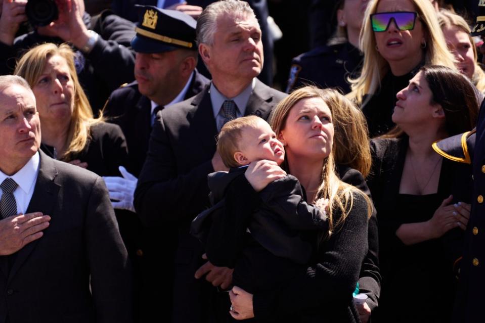 Stephanie Diller, wife of slain NYPD officer Jonathan Diller, holds their son, Ryan, during her husband’s funeral at St. Rose of Lima Roman Catholic Church on Saturday in Massapequa. James Keivom