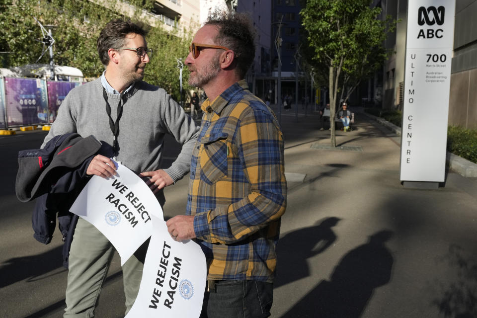 Two men arrive as Australian Broadcasting Corp. (ABC) workers and other supporters gather at the ABC offices in Sydney, Monday, May 22, 2023, to support Indigenous journalist Stan Grant. Grant announced he would step away from television hosting duties after viewers responded with racist abuse to his comments during King Charles III's coronation about historic Aboriginal dispossession. (AP Photo/Rick Rycroft)