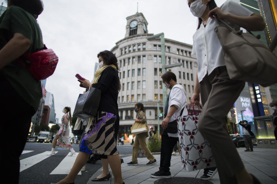 People wearing face masks walk across a traffic intersection in the Ginza shopping district of Tokyo during a state of emergency on Thursday, Sept. 30, 2021. On Friday, Oct. 1, 2021, Japan fully came out of a coronavirus state of emergency for the first time in more than six months as the country starts gradually easing virus measures to help rejuvenate the pandemic-hit economy as the infections slowed.(AP Photo/Hiro Komae)