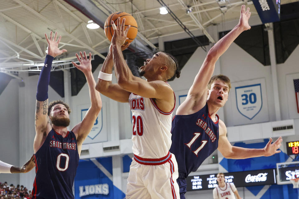 Loyola Marymount guard Cam Shelton, center, shoots between Saint Mary's center Mitchell Saxen, right, and guard Logan Johnson during the second half of an NCAA college basketball game Thursday, Feb. 9, 2023, in Los Angeles. Loyola Marymount won 78-74. (AP Photo/Ringo H.W. Chiu)