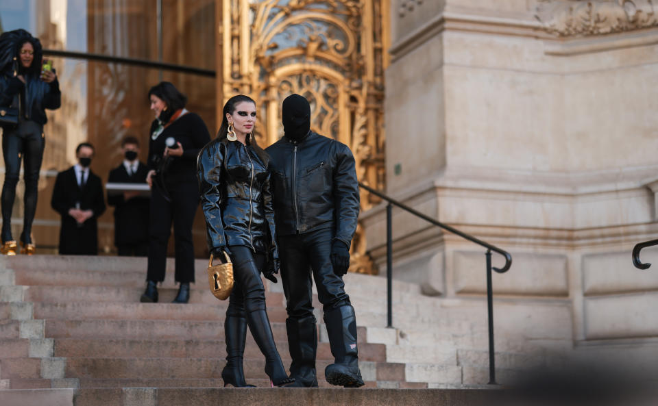Julia Fox wears and all leather look and stands next to Kanye West in a balaclava. (Getty Images)