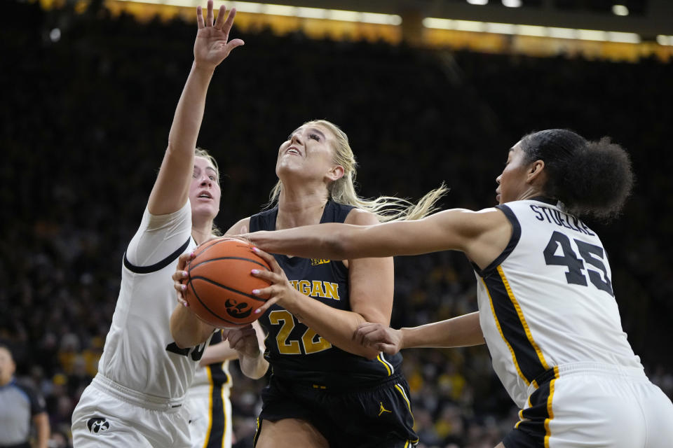 Michigan forward Chrya Evans (22) is fouled by Iowa forward Hannah Stuelke (45) while guard Kate Martin (20) defends during the first half of an NCAA college basketball game Thursday, Feb. 15, 2024, in Iowa City, Iowa. (AP Photo/Matthew Putney)