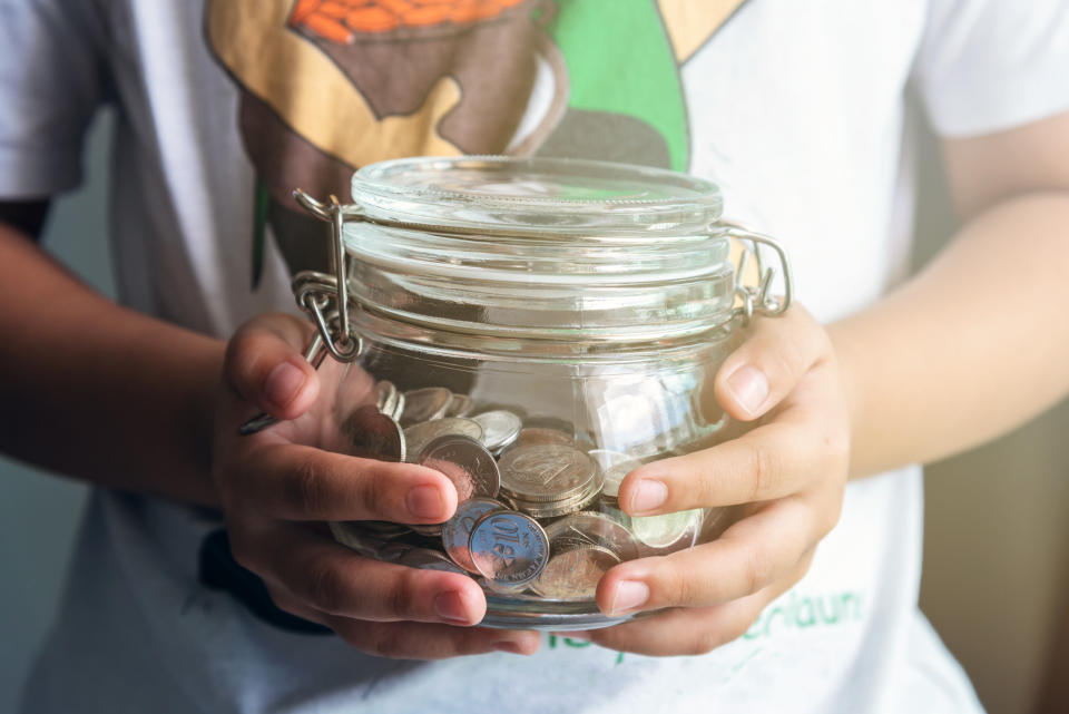 A kid holds a jar of coins