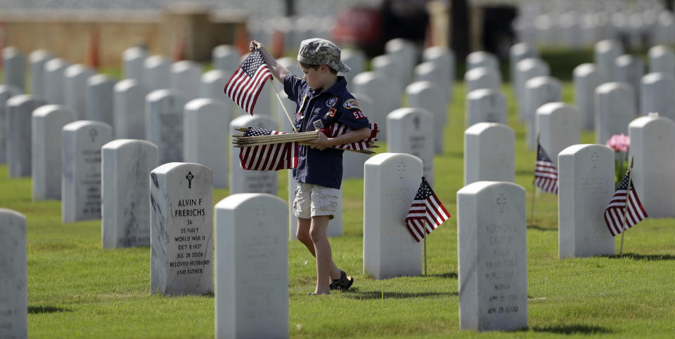 <p>A Boy Scout helps place some of the more than 100,000 U.S. flags next to headstones at Fort Sam Houston National Cemetery in preparation of Memorial Day, Friday, May 25, 2018, in San Antonio. Texas. (Photo: Eric Gay/AP) </p>