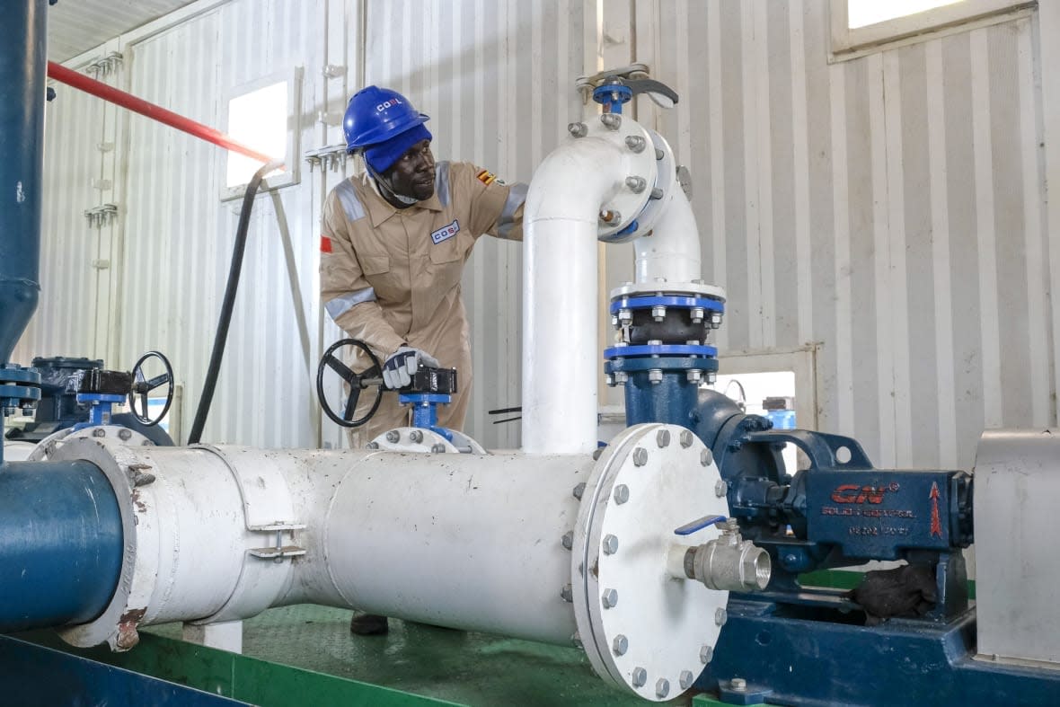 A Ugandan worker from China Oilfield Services Limited (COSL), a contractor for China National Offshore Oil Corporation (CNOOC), inspects pipes on the drilling rig at the Kingfisher oil field on the shores of Lake Albert in the Kikuube district of western Uganda Tuesday, Jan. 24, 2023. Oil drilling began Tuesday at the Chinese-operated oil field and the East African country expects to start production by 2025, a government official said. (AP Photo/Hajarah Nalwadda)