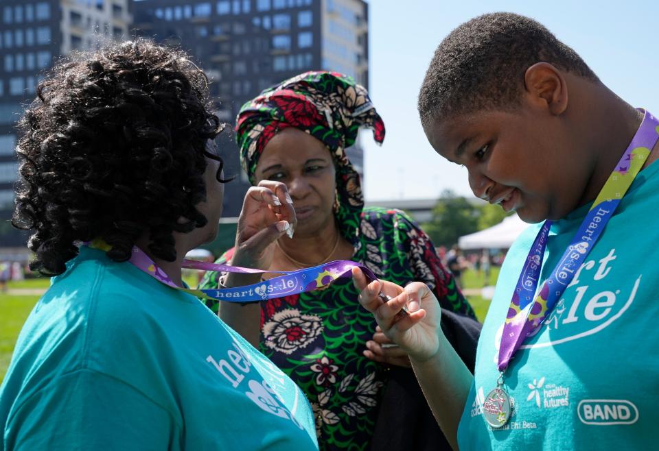 Mary Elizabeth Nnachetam looks at the medal around the neck of Coach Reva McHardy, who was signing to Patricia Nnachetam, Mary Elizabeth’s mother, after the Girls on the Run spring 5K Sunday.