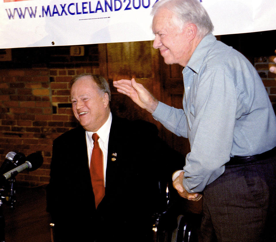 FILE - Former President Jimmy Carter, right, gives U.S. Sen. Max Cleland, D-Ga., a standing ovation during Cleland's campaign rally in Carter's rural hometown of Plains, Ga., Oct. 25, 2002. Cleland, who lost three limbs to a Vietnam War hand grenade blast yet went on to serve as a U.S. senator from Georgia, died on Tuesday, Nov. 9, 2021. He was 79. (AP Photo/Walter Petruska, file)