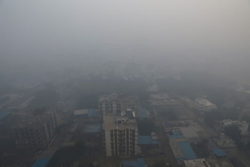 FILE PHOTO: Residential buildings are seen shrouded in smog in Noida