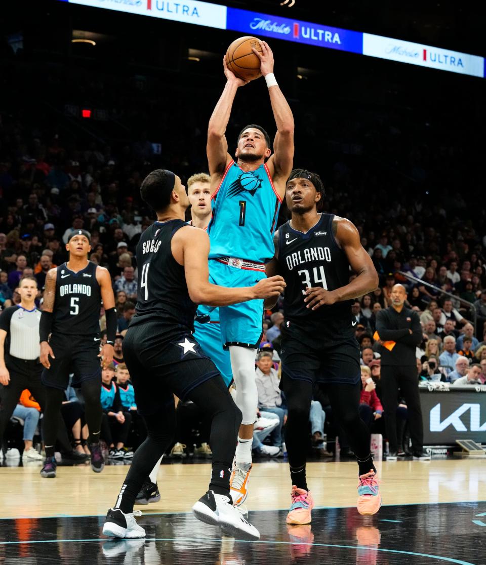 Phoenix Suns guard Devin Booker (1) takes a shot over Orlando Magic guard Jalen Suggs (4) in the first half at Footprint Center in Phoenix on March 16, 2023.