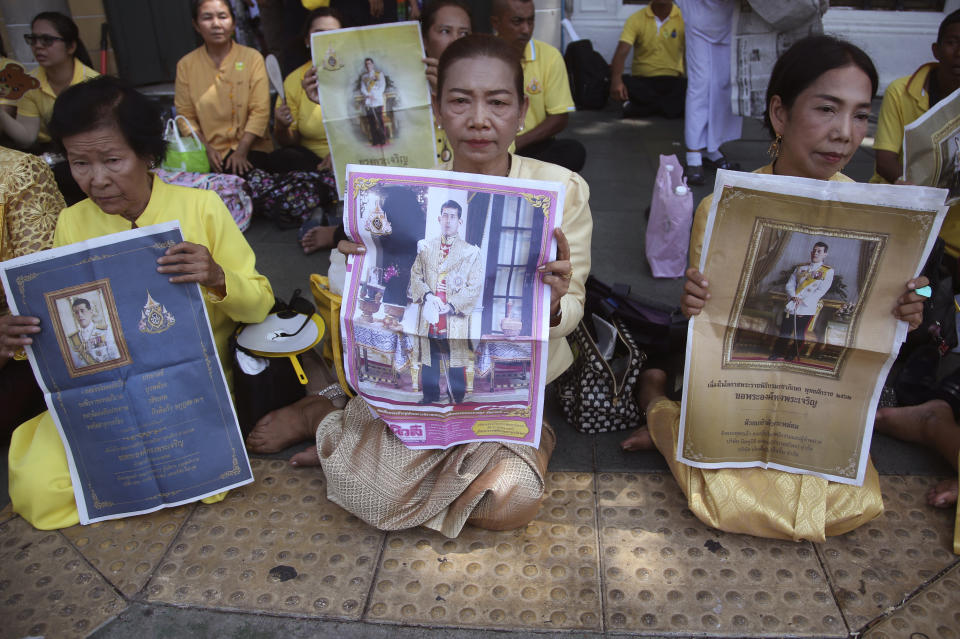 Thai well-wishers hold the portraits of Thailand's King Maha Vajiralongkorn outside the Grand Palace in Bangkok, Thailand, Sunday, May 5, 2019. King Maha Vajiralongkorn was officially crowned amid the splendor of the country's Grand Palace, taking the central role in an elaborate centuries-old royal ceremony that was last held almost seven decades ago.(AP Photo/Sakchai Lalit)