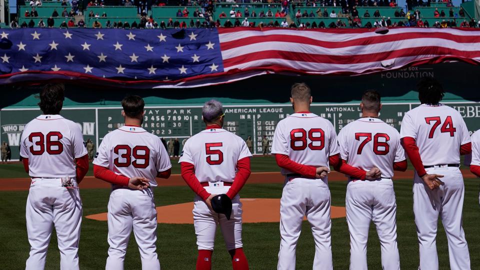 Boston Red Sox players stand for the national anthem as a giant flag is unfurled prior to an opening day baseball game against the Baltimore Orioles, Thursday, March 30, 2023, in Boston. (AP Photo/Charles Krupa)