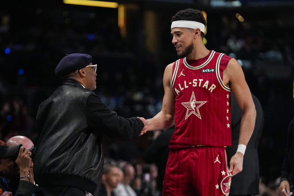 Phoenix Suns guard Devin Booker (1) shakes hands with Spike Lee during the second half of an NBA All-Star basketball game in Indianapolis, Sunday, Feb. 18, 2024. (AP Photo/Darron Cummings)