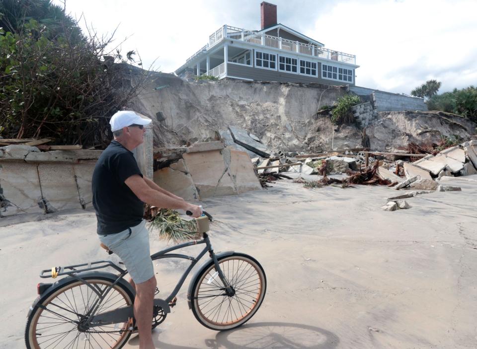 A cyclist checks out homes damaged by Tropical Storm Nicole, Friday, Nov. 11, 2022, in Wilbur-by-the-Sea.