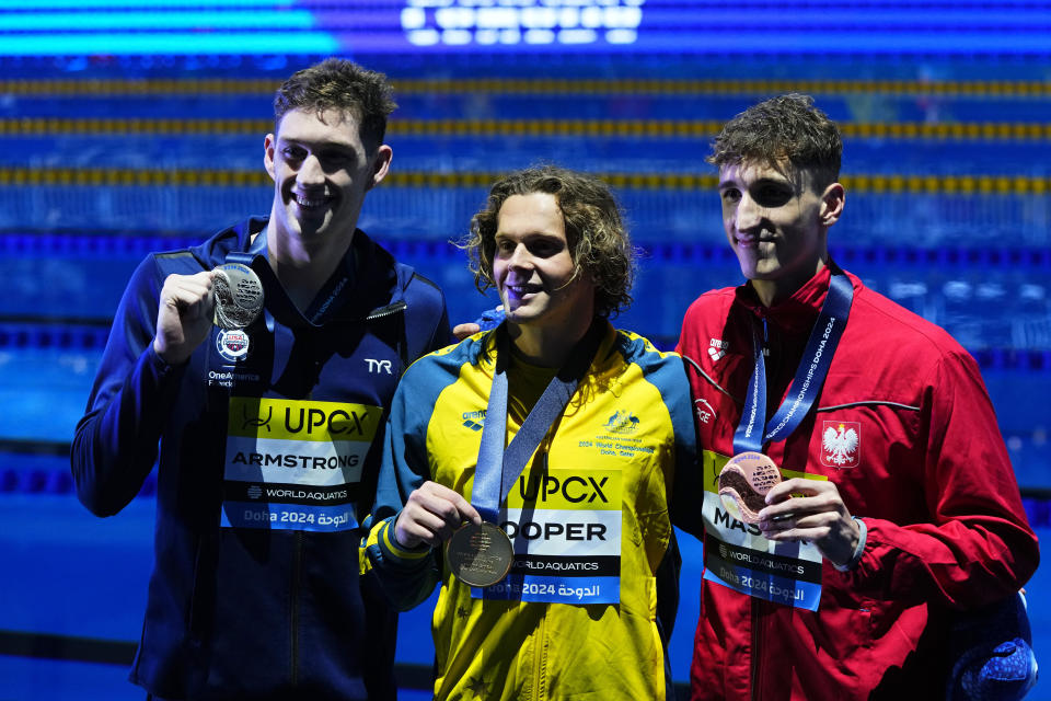 Silver medalist Hunter Armstrong of the United States, gold medalist Isaac Cooper of Australia and bronze medalist Ksawery Masiuk of Poland, from left to right, pose after the Men's 50m Backstroke final at the World Aquatics Championships in Doha, Qatar, Sunday, Feb. 18, 2024. (AP Photo/Hassan Ammar)