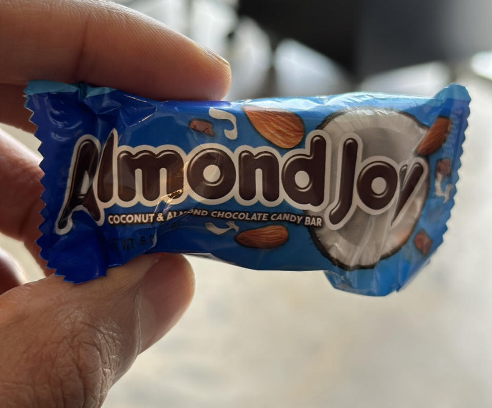 A hand holding a small bag of Almond Joy Coconut & Almond Chocolate Candy Bar